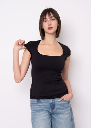 Woman wearing a black top and blue jeans against a white background